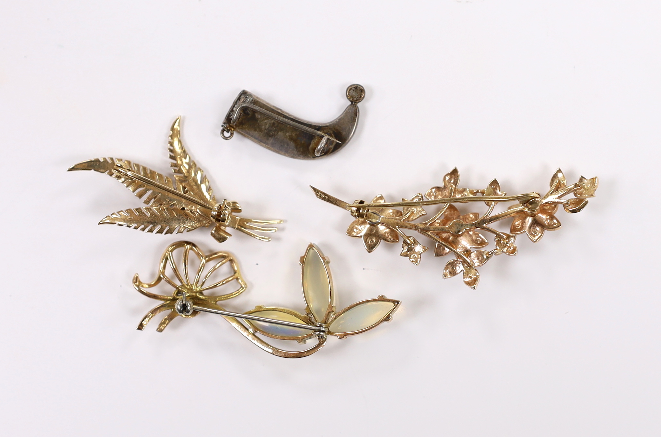 Three assorted modern 9ct and gem set foliate brooches, including garnet, seed pearl and jelly opal, largest 54mm, gross weight 16.4 grams and a white metal filigree brooch.